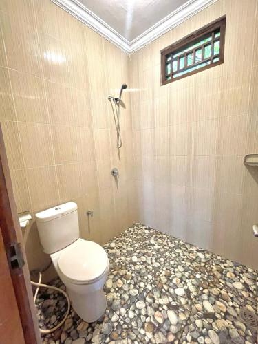 a bathroom with a toilet and a rock floor at Sekumpul Accommodation in Singaraja