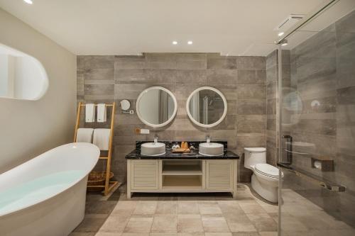 a bathroom with a tub and a toilet and mirrors at 莫干山缦田生态度假酒店 in Deqing