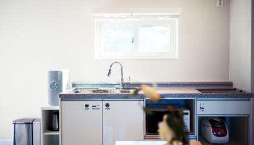 a kitchen with white cabinets and a sink and a window at Opus11 Poolvilla in Gyeongju
