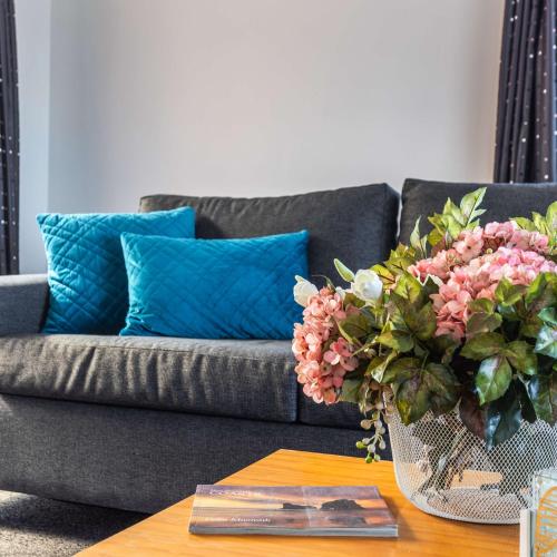 a living room with a couch and a table with a vase of flowers at Ika Nui Taupo in Taupo