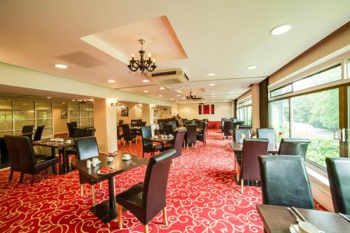 a restaurant with tables and chairs on a red carpet at The Bridge House Hotel in Reigate