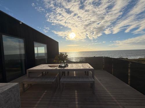 a wooden deck with a table and benches and the ocean at King Island Lodge - North & South Lodge in Currie