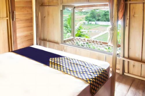 a bed in a room with a window at Hotel O Bale Kertiasih Near SMPN Satap 4 GANGGA in Labuan Lombok