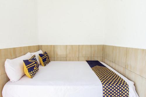 a bed with four pillows on top of it at Hotel O Penginapan Mekar Sari Near PT. Lombok Menara Energygas in Kuripan