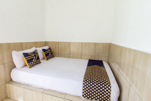 a bed in a small room with two pillows on it at Hotel O Penginapan Mekar Sari Near PT. Lombok Menara Energygas in Kuripan