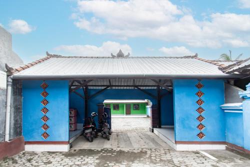 a blue house with two motorcycles parked in front at Hotel O Penginapan Mekar Sari Near PT. Lombok Menara Energygas in Kuripan