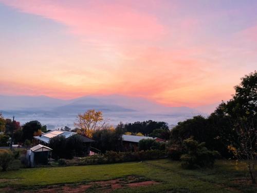 a sunset over a field with a house at Mount Emu Views in Tawonga