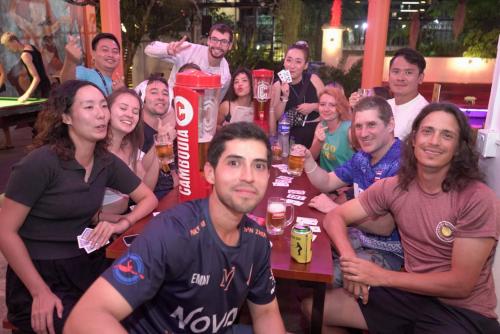 a group of people sitting around a table with beer at Bliss & Beats Hostel in Phnom Penh