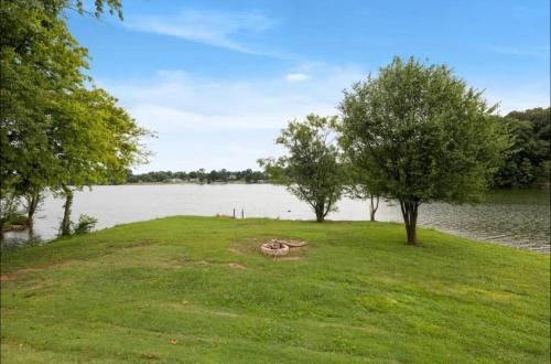 a grassy area with trees and a body of water at The Modern Mainstay at Barefoot Bay in Winchester