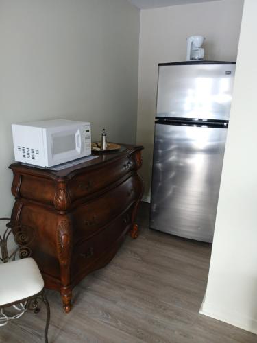 a microwave on a wooden dresser next to a refrigerator at Hotel Oasis Lac St-Louis in Salaberry de Valleyfield