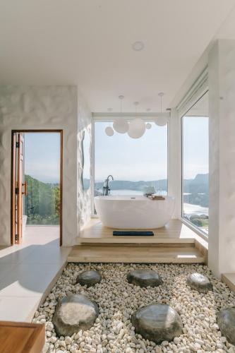a bathroom with a tub and rocks on the floor at Make me see cloud - Chiang rai in Mae Suai