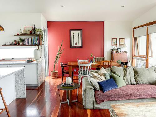 a living room with a couch and a red wall at Byron Butter Factory Apartments in Byron Bay