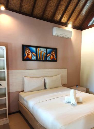 a bedroom with a bed and a tv on the wall at Si Pitung Village in Gili Air