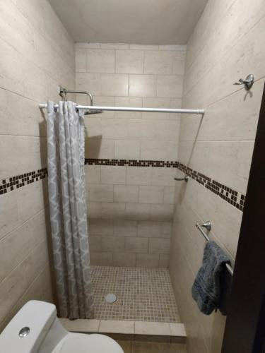 a bathroom with a shower with a toilet and a shower curtain at La Quinta Departamentos in Hermosillo