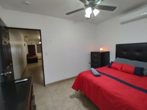 a bedroom with a red bed and a ceiling fan at La Quinta Departamentos in Hermosillo