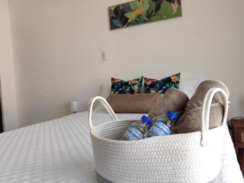 a basket filled with water bottles sitting on a bed at Hotel Boutique CasAguacate close to Airport, Pedregal, Centro de Convenciones de Costa Rica in Potrerillos