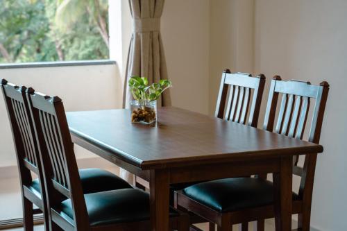 a wooden table with four chairs and a vase on it at Nanu Beach Resort & Spa in Betalbatim