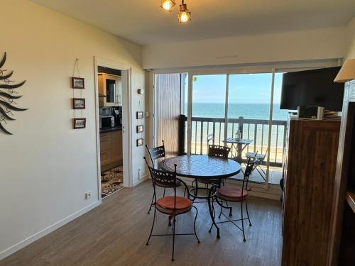 une salle à manger avec une table et des chaises et l'océan dans l'établissement Studio en bord de mer avec balcon et vue imprenable, accès direct plage - FR-1-487-317, à Cabourg