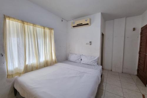 a small bedroom with a white bed and a window at Hotel O Wira Residensia Syariah in Medan