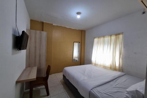 a bedroom with a bed and a table and a window at Hotel O Wira Residensia Syariah in Medan