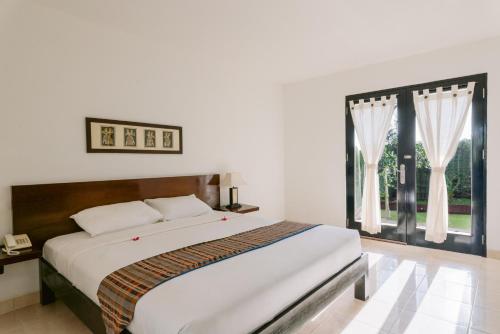 a bedroom with a large bed and a window at Legong Keraton Beach Hotel in Canggu