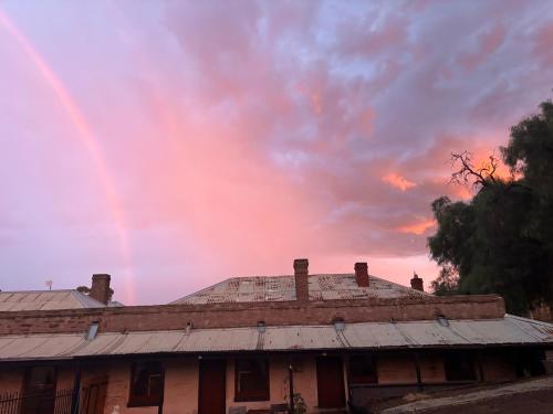 an old brick house with a rainbow in the sky at The Smelters Home Burra in Burra