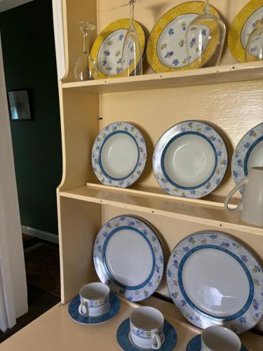a shelf filled with blue and white plates and cups at The Smelters Home Burra in Burra