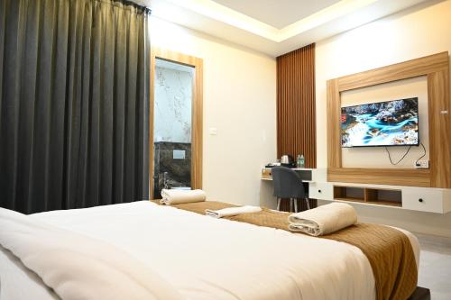 um quarto de hotel com duas camas e uma televisão em The Janki Hotel em Ayodhya