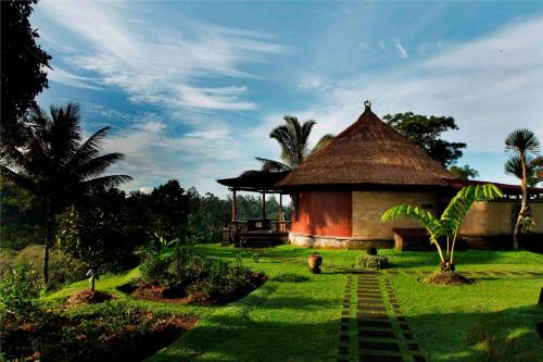 a hut with a grass roof in a field at Bagus Jati Health & Wellbeing Retreat in Tegalalang