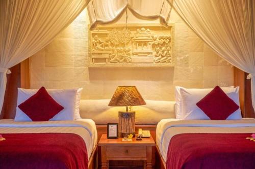 a bedroom with two beds with red and white pillows at Bagus Jati Health & Wellbeing Retreat in Tegalalang