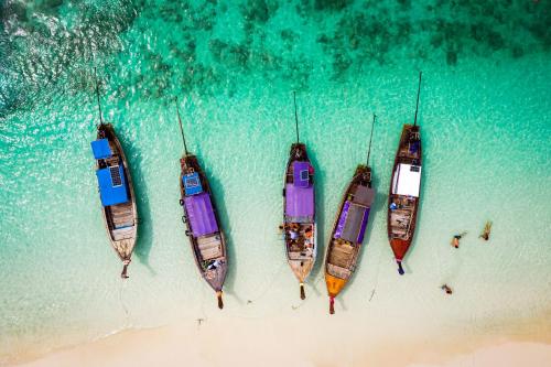 three boats parked on a beach next to the water at BJ & Radisson Sea View Hotel in Ko Yao Yai