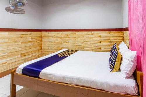 a bedroom with a bed with a wooden headboard at Hotel O De Lanang Homestay Near Masjid Janapria in Papak