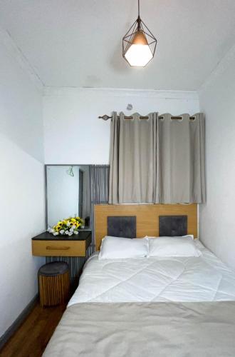 a bedroom with a white bed and a window at Woods Cottage Kilimani in Nairobi