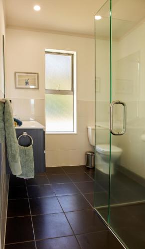 a bathroom with a shower and a toilet and a sink at Ruru House in Auckland