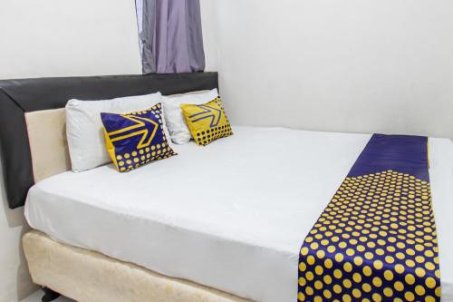 a bed with yellow and blue pillows on it at Hotel O Penginapan Melati Tanjung Near Kantor Pengamat Pengairan Tanjung in Papak