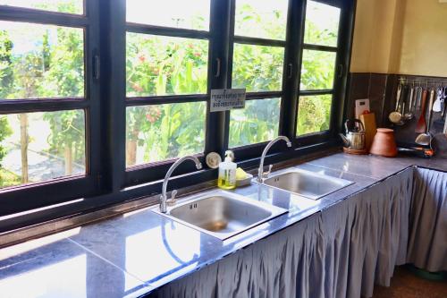a kitchen counter with two sinks in front of windows at Morimei Khaoyai in Ban Khlong Yang