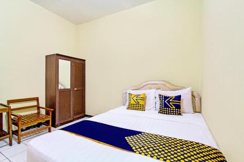 a bedroom with a bed with yellow and blue pillows at Hotel O Juan Guest House in Purwokerto