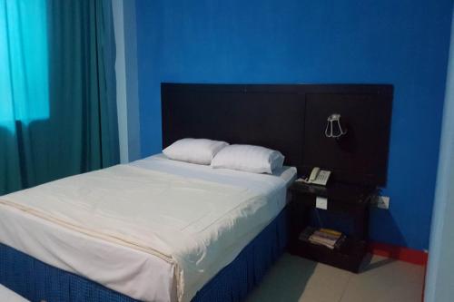 a bedroom with a bed with a blue wall at Hotel O Wisma Haji BunbunNearYani Heahlerr in Rantau