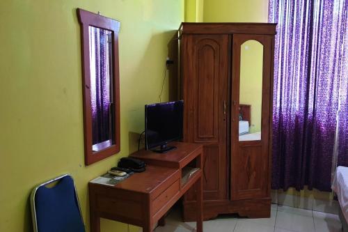 a room with a desk with a computer and a mirror at Hotel O Wisma Haji BunbunNearYani Heahlerr in Rantau