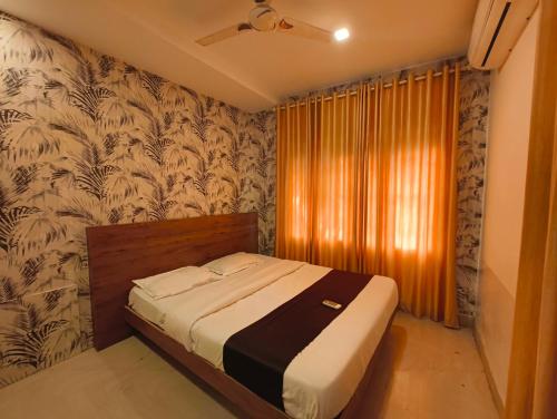 a bedroom with a bed in a room with wallpaper at Comfort INN in Payyannūr