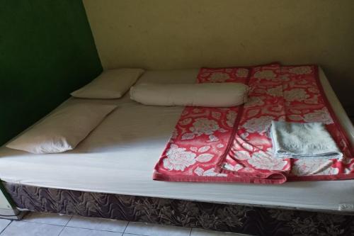 a bed with red and white blankets and pillows at Hotel O Pondok Gusang Kuala Near Pelabuhan H Basran in Pagatan