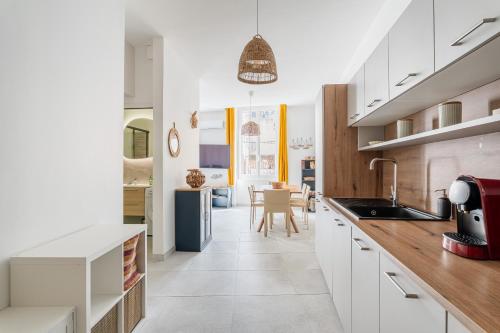 une cuisine avec des placards blancs et une salle à manger dans l'établissement L'Icare par Dodo à Cassis, à Cassis