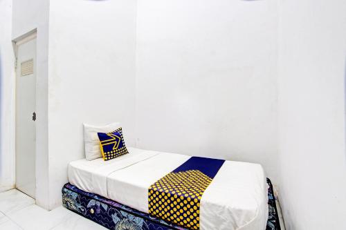 a bed in a room with a white wall at Hotel O Agus Kostel SyariahNearWisata Agro Jollong in Gembong