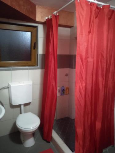 a bathroom with a toilet and a red shower curtain at Apartments Popovic in Podgorica