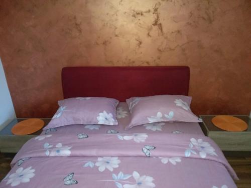 a bed with pink sheets and white flowers on it at Apartments Popovic in Podgorica