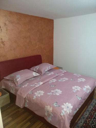 a bed with a pink comforter and pillows at Apartments Popovic in Podgorica