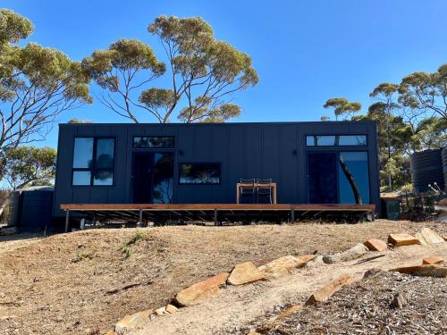 美洲河Essence Kangaroo Island - Tiny home American River的树荫山顶上的黑色房子