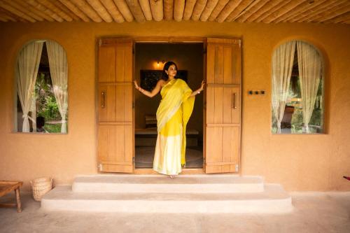 a woman in a yellow dress standing in a doorway at The Mudhouse Marayoor in Munnar