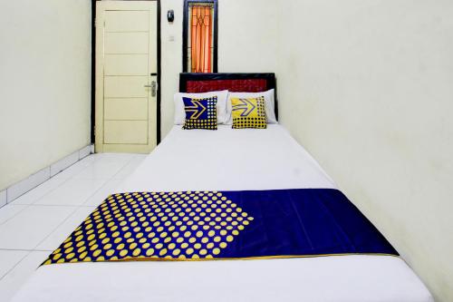 a bed with a blue and white blanket on it at OYO Life 93260 Bale Kosan in Tanjung