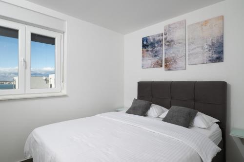 ein weißes Schlafzimmer mit einem großen Bett und einem Fenster in der Unterkunft Sunshine Bay II in Nona